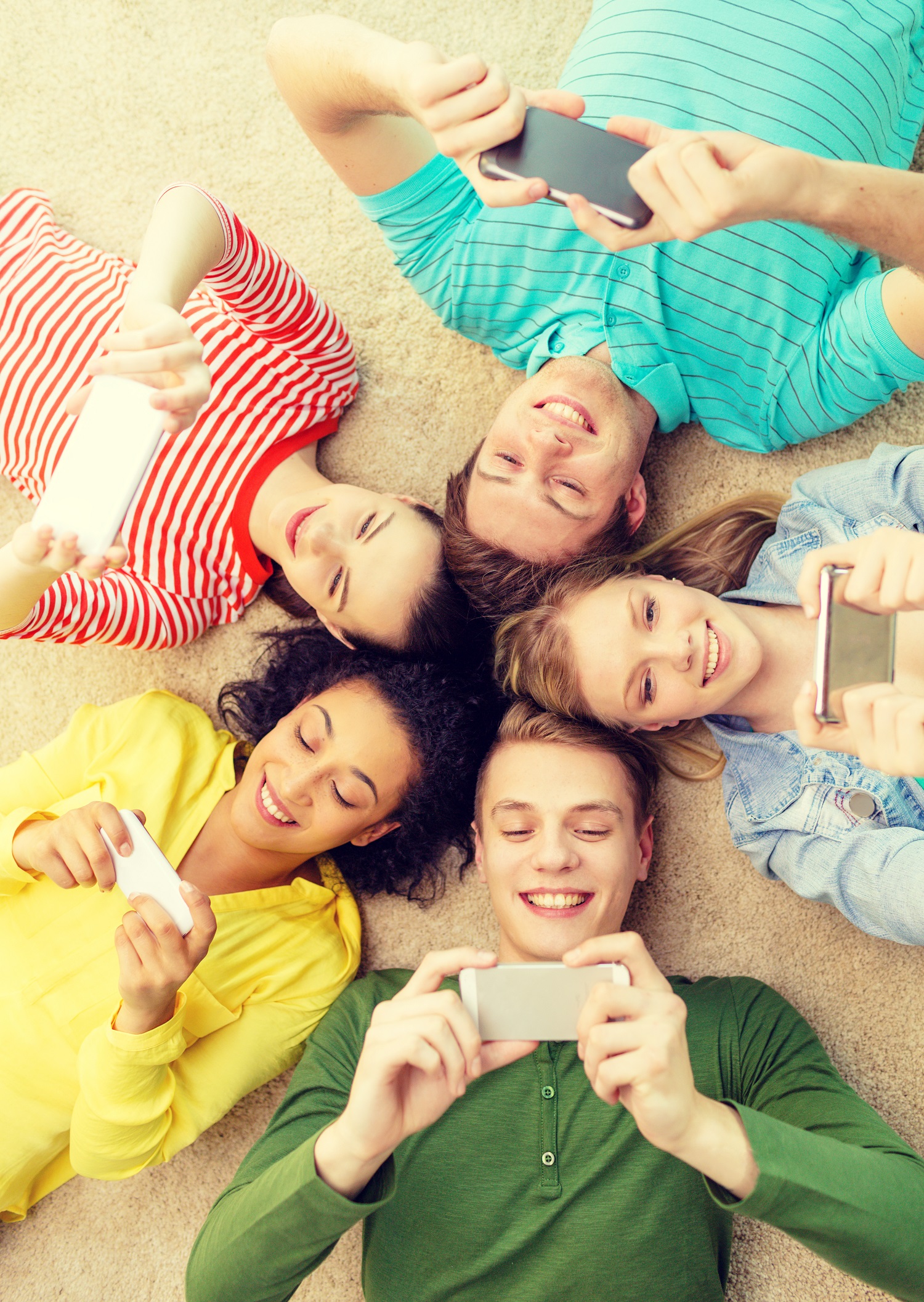 Gruppe Jugendliche mit Smartphones liegen auf dem Boden