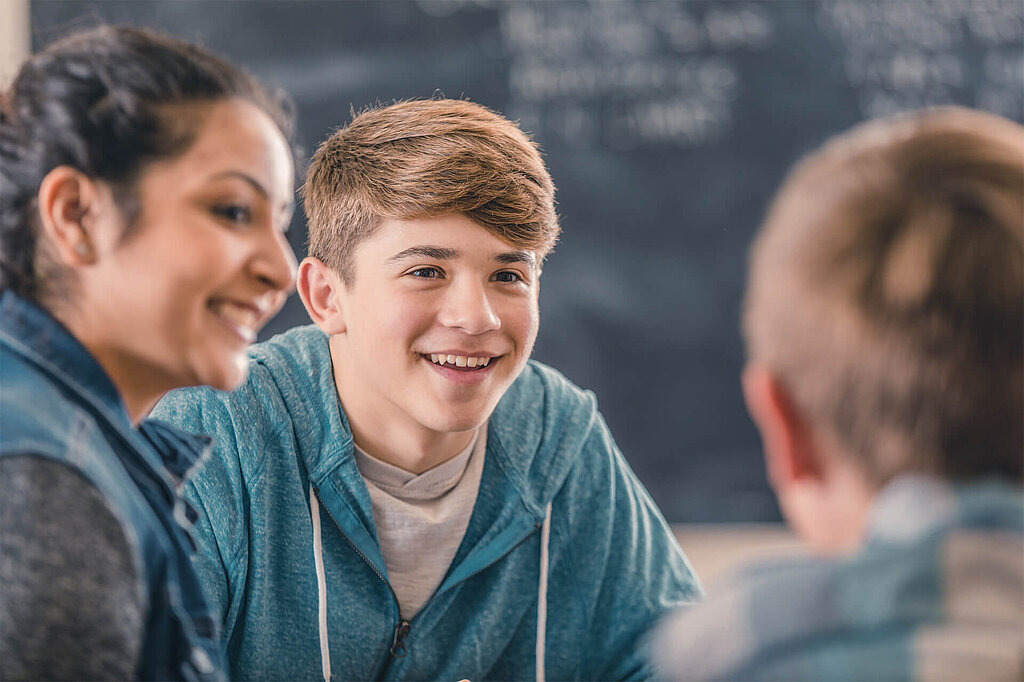 Drei Jugendliche diskutieren gemeinsam im Klassenzimmer.
